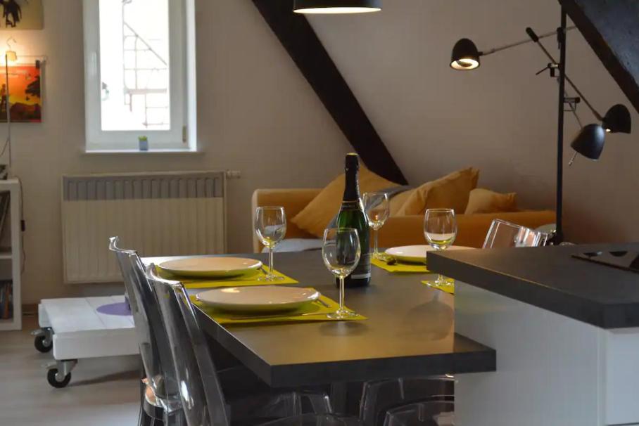 einen Esstisch mit einer Flasche Wein und Gläsern in der Unterkunft Bretzel & Raisin - Hypercentre de Colmar in Colmar