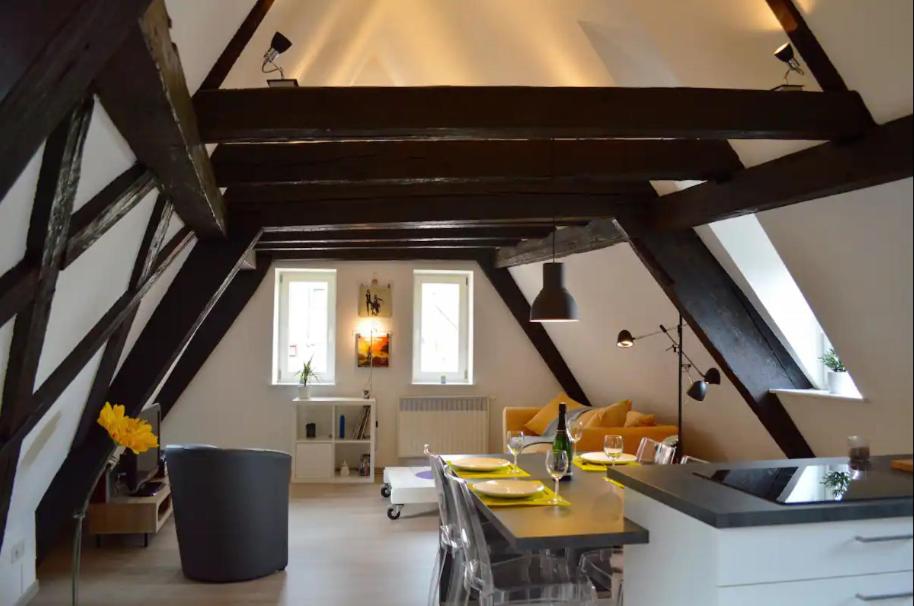 a kitchen and living room with wooden ceilings and a table at Bretzel &amp; Raisin - Hypercentre de Colmar in Colmar