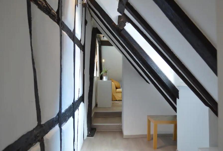 an attic hallway with stairs and a table and a chair at Bretzel &amp; Raisin - Hypercentre de Colmar in Colmar