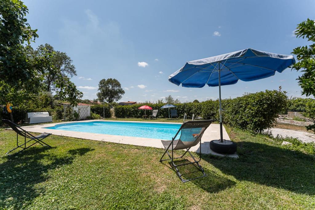 um guarda-sol azul e cadeiras junto a uma piscina em Contemporary countryside haven in Mangualde em Mangualde