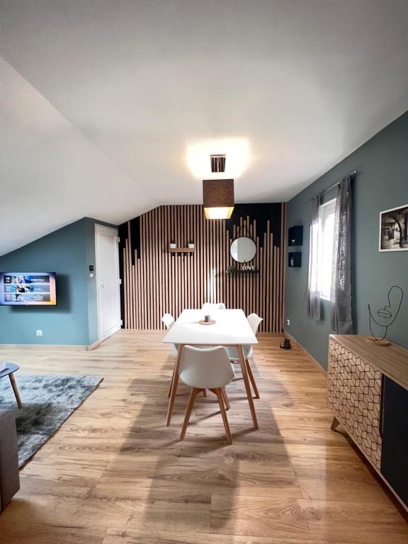 une salle à manger avec une table blanche et des murs bleus dans l'établissement Appartement 400 m du centre, à Louhans