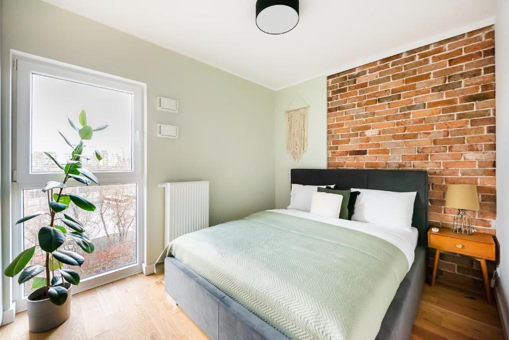 a bedroom with a bed and a brick wall at Bohema Place - Metro Szwedzka Apartment in Warsaw