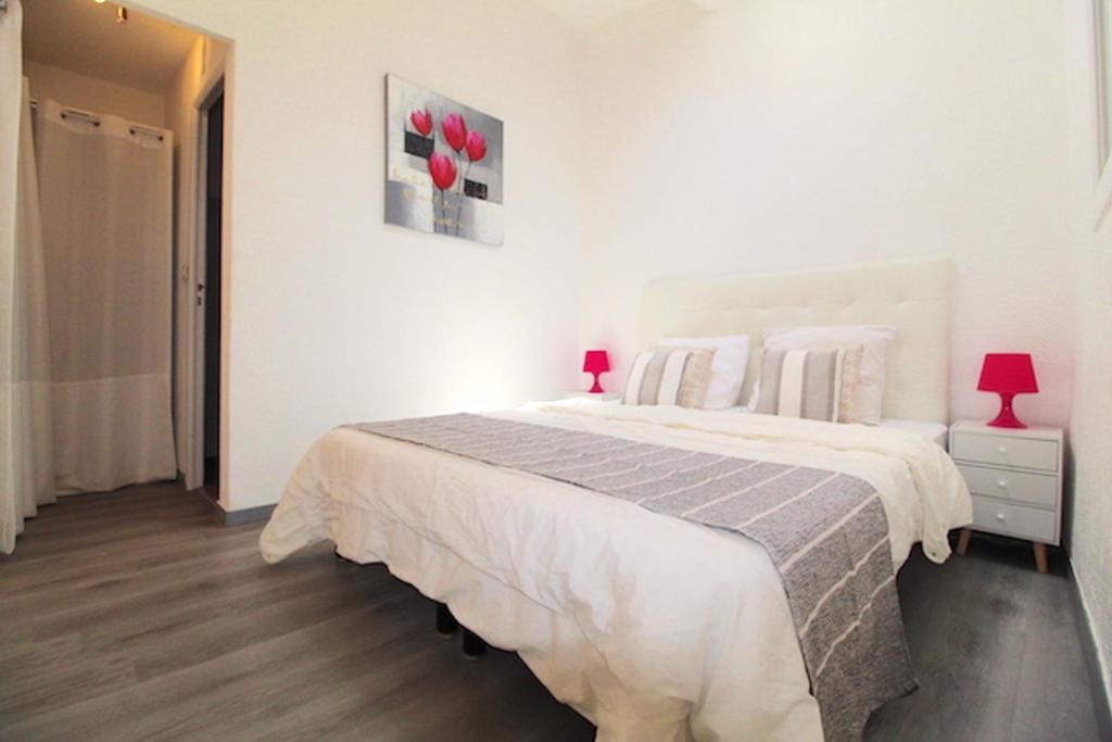 une chambre blanche avec un grand lit avec des fleurs rouges sur le mur dans l'établissement Appartement moderne à Cannes, 45 m², proche des plages, à Cannes