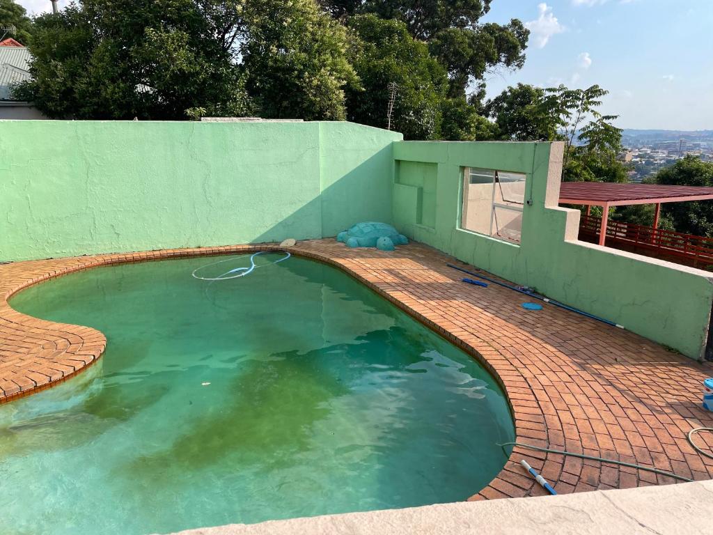 a swimming pool with a brick floor and a green house at Lorentzville in Johannesburg