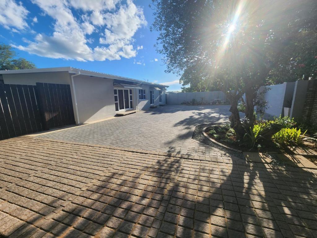 a driveway in front of a house with a tree at Gateway@134 Guesthouse in Vryheid