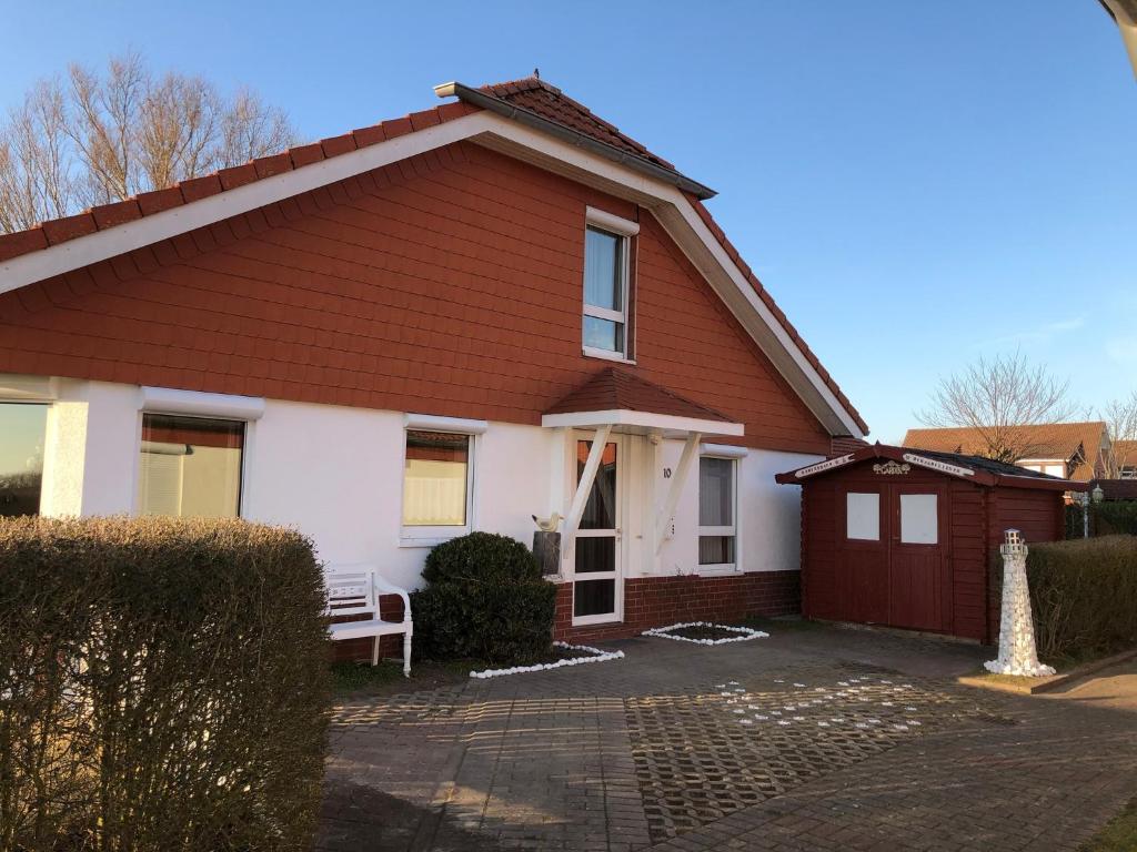 una casa marrón y blanca con un banco en la entrada en Ferienhaus Strandflieder en Dorum Neufeld