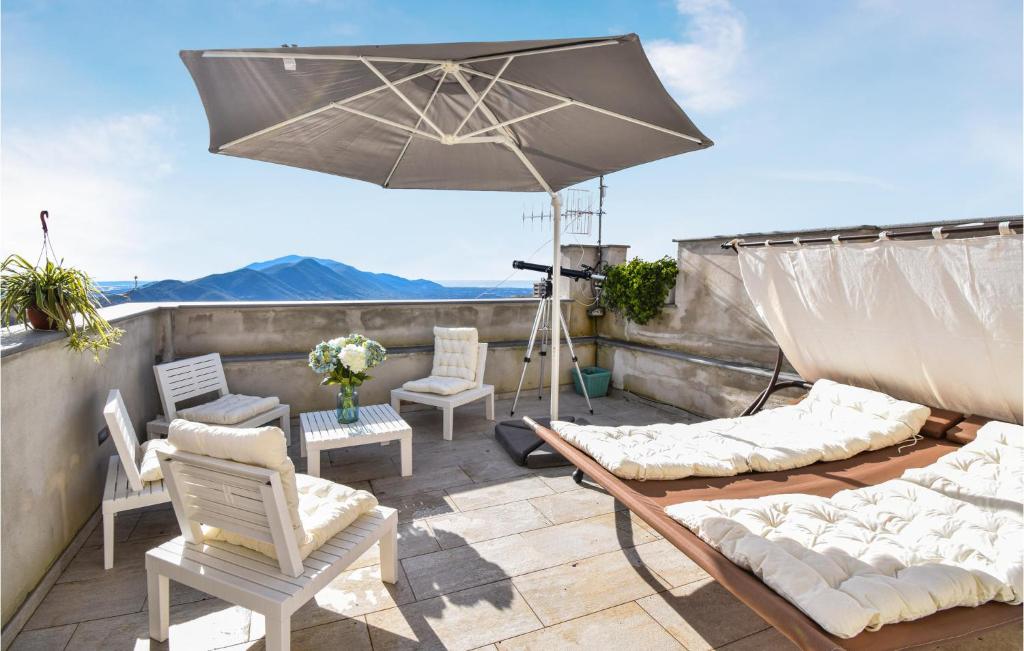 un patio avec des chaises et un parasol sur le toit dans l'établissement Gorgeous Apartment In Sessa Aurunca With Kitchen, à Sessa Aurunca