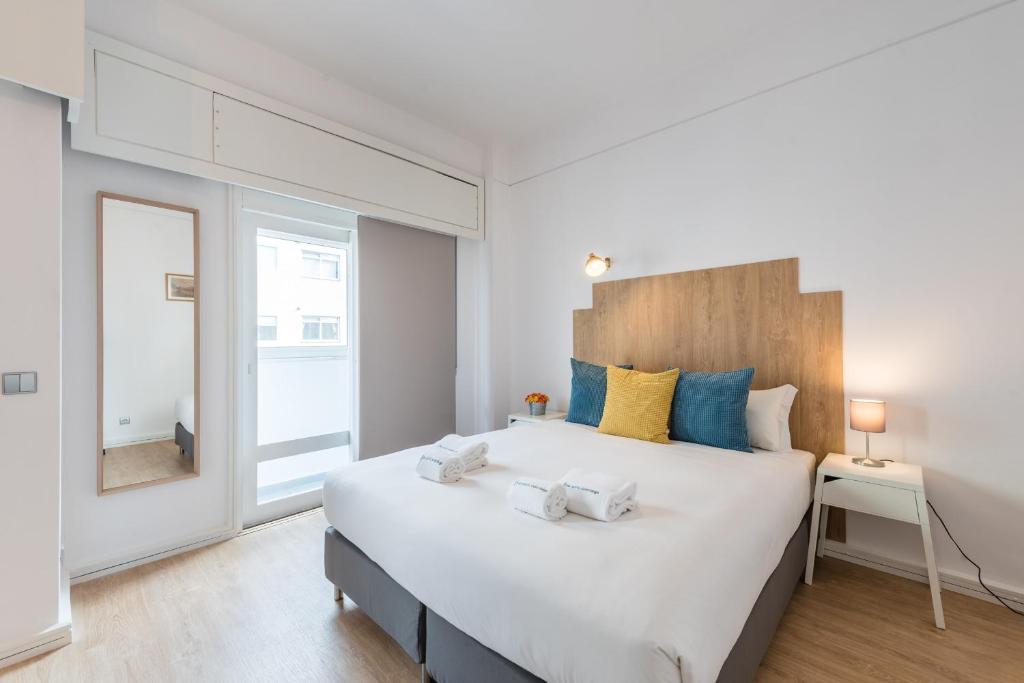 una camera da letto con un grande letto bianco con cuscini blu e gialli di GuestReady - Music Flats 2 a Porto