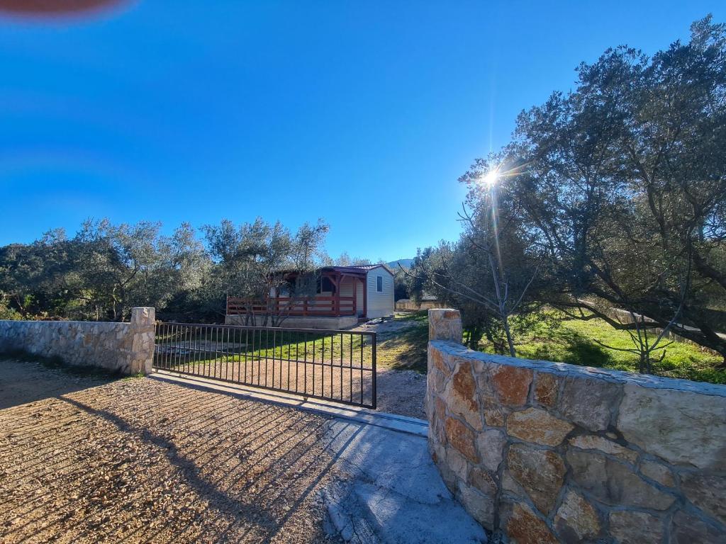 a gate in a stone wall with a house in the background at Gabi Mobile home in Banj