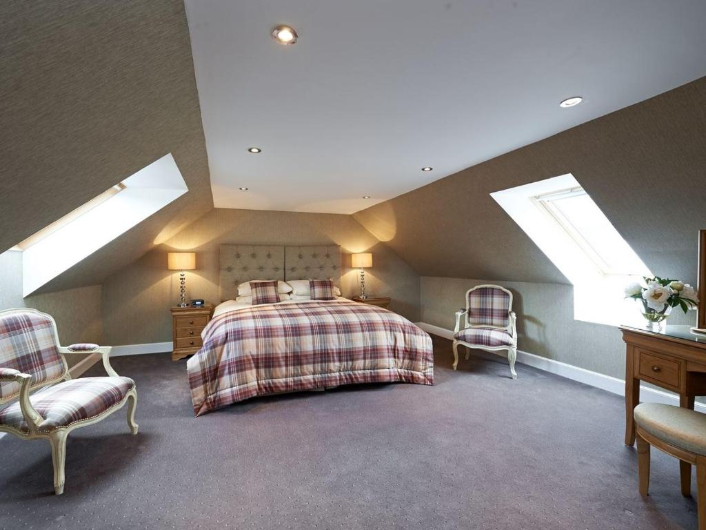 a attic bedroom with a bed and two chairs at Home Farm Cottages, Glendaruel, Argyll. Scotland in Clachan of Glendaruel