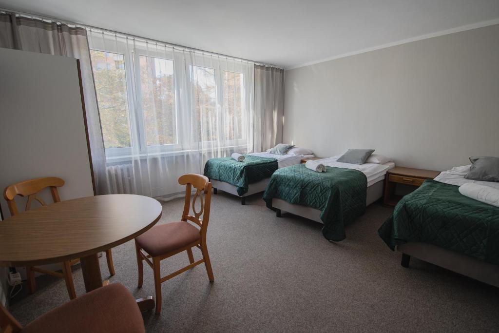 Cette chambre comprend deux lits, une table et des chaises. dans l'établissement Hotel Felix, à Cracovie