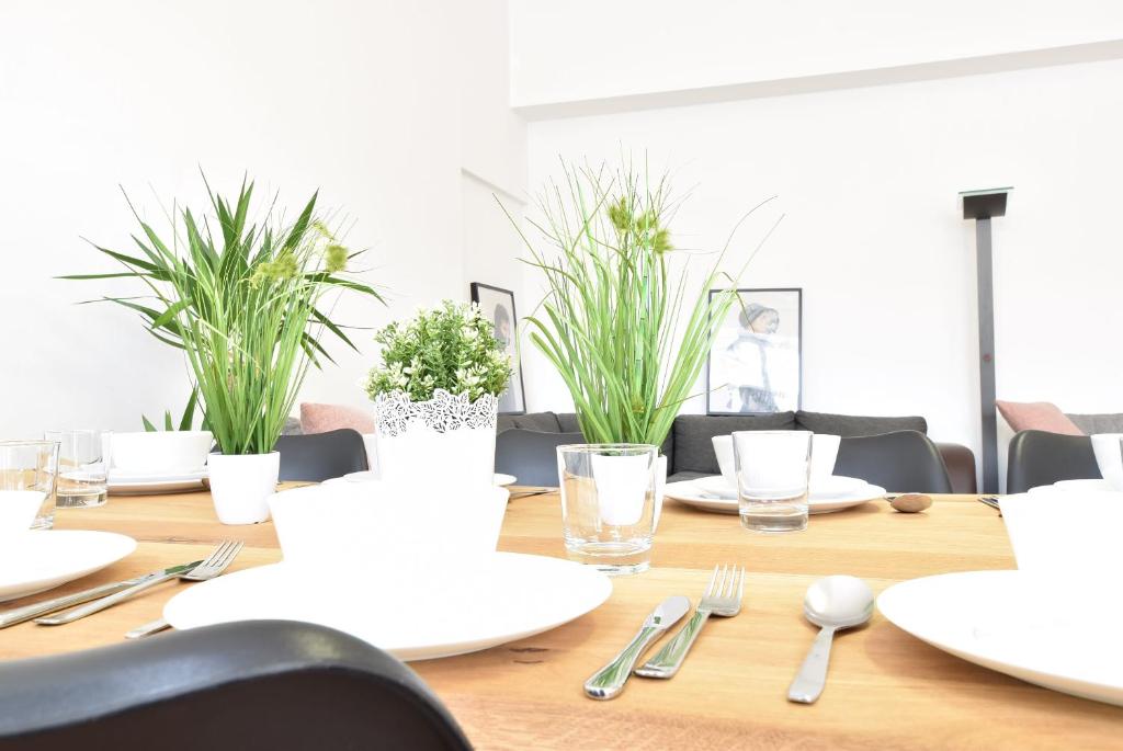 einem Holztisch mit weißen Tellern, Besteck und Pflanzen in der Unterkunft Riesiges zentrales Apartment mit Parkplatz in Innsbruck