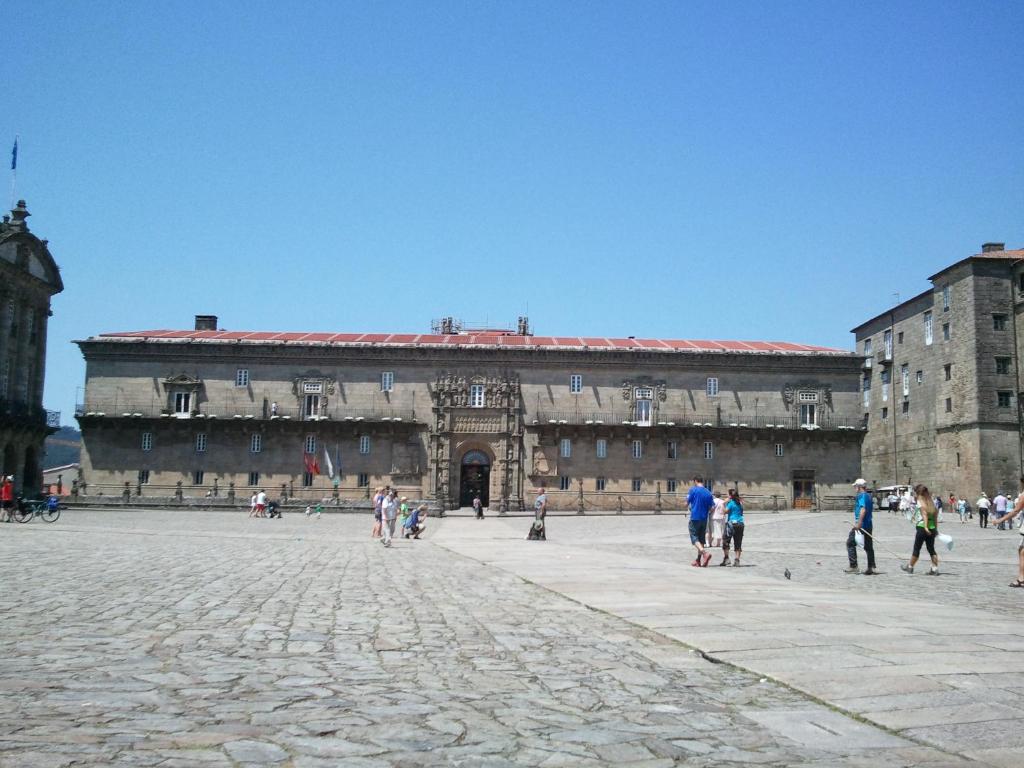 a large building with people walking around it at Parador de Santiago - Hostal Reis Catolicos in Santiago de Compostela