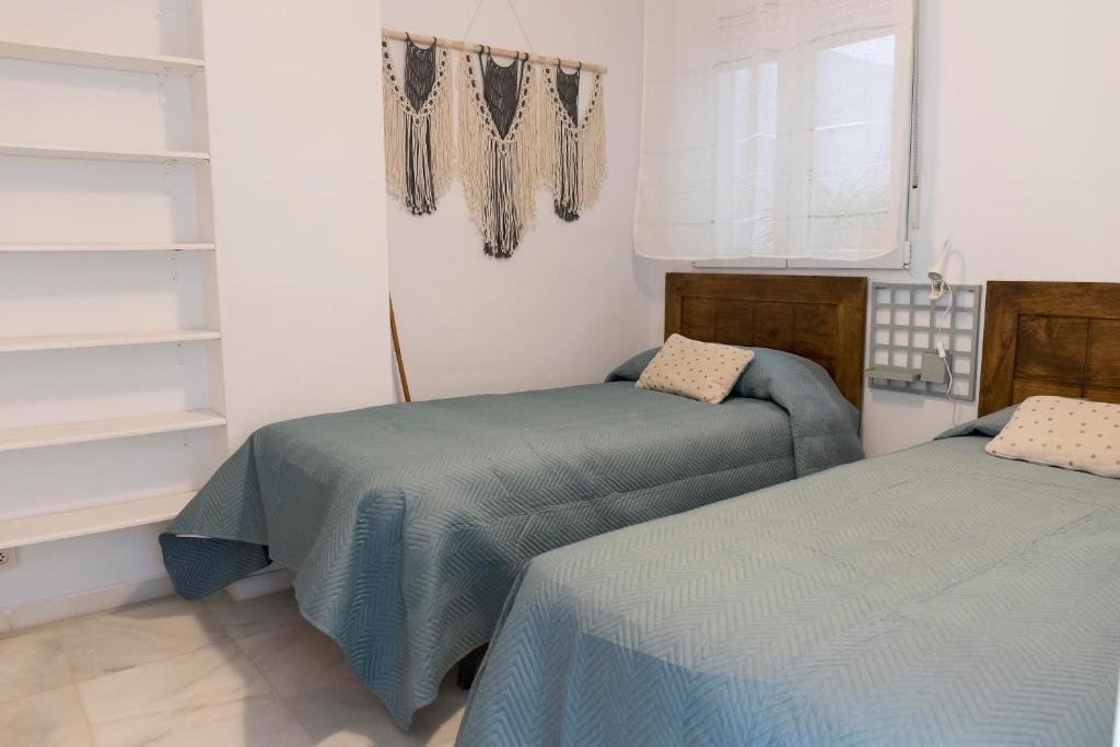 a bedroom with two beds and a window and shelves at Titan, edificio Hipercor, con Parking in Huelva