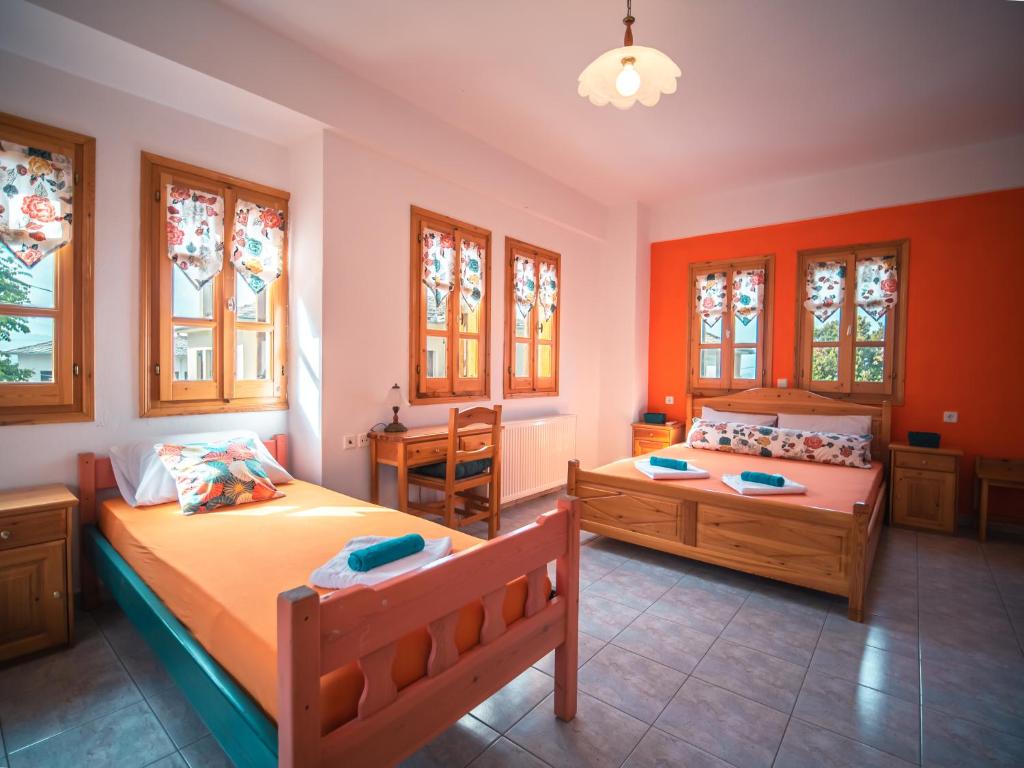 2 Betten in einem Zimmer mit orangefarbenen Wänden und Fenstern in der Unterkunft Orange House for big families in Damouchari - Delicious Houses in Damouchari