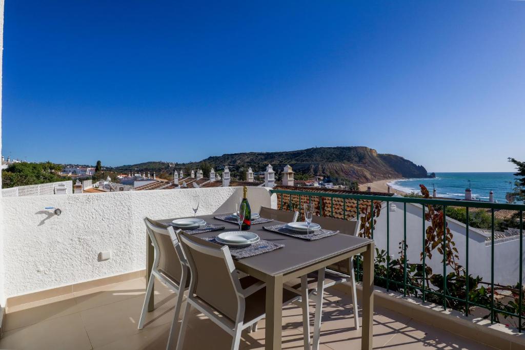 una mesa y sillas en un balcón con vistas al océano en Casa Rujo - Waterside Village House en Luz