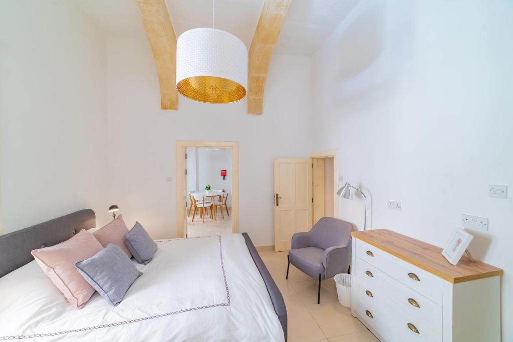 ein Schlafzimmer mit einem weißen Bett mit rosa und blauen Kissen in der Unterkunft Carmelita Maisonette Valletta in Valletta