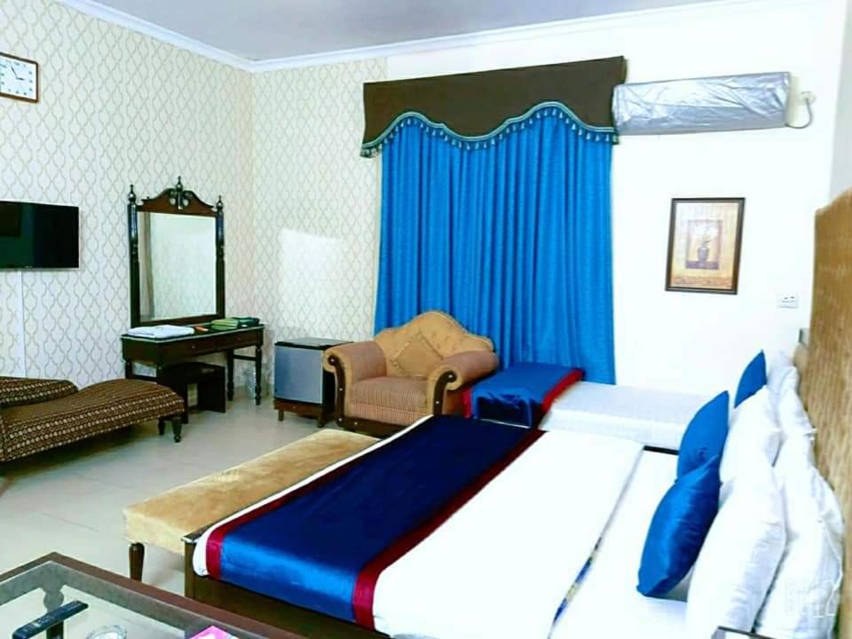 拉合爾的住宿－New Pakeeza Hotel，一间卧室配有一张大床和蓝色窗帘