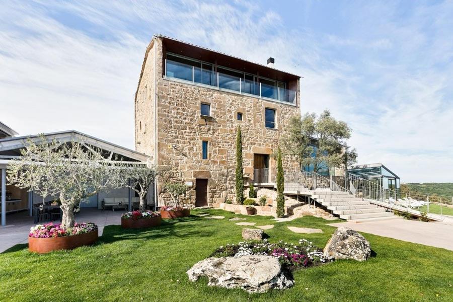 un gran edificio de piedra con algunas rocas en el césped en Catalunya Casas Fabulous Villa for 28 with Heated Pool, en Torá de Rulbregos