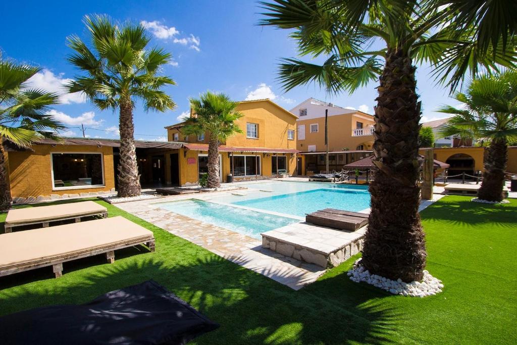 a swimming pool with palm trees in front of a house at Catalunya Casas Relax and Recharge - only 34km from Barcelona! in Rubí