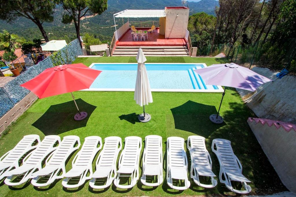 a group of chairs and umbrellas next to a pool at Catalunya Casas Fun and Frolic in Lloret del Mar 3500 meters to beach! in Lloret de Mar