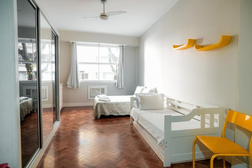 Un dormitorio con 2 camas y una silla. en Apartamento confortável na quadra da praia, en Río de Janeiro
