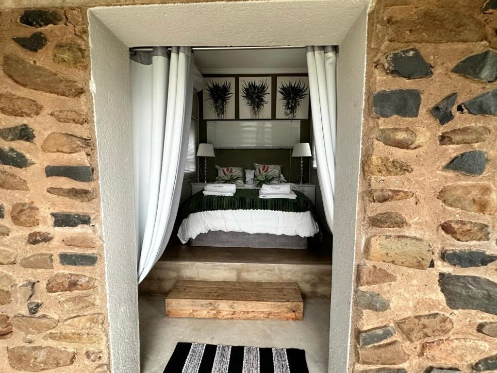 una camera da letto con un grande letto con tende bianche di Hazyview Accommodation, Bon Repose Cottage 2 a Hazyview