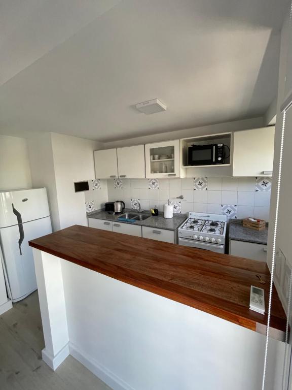 a kitchen with white cabinets and a wooden counter top at Temporario 48 in La Plata