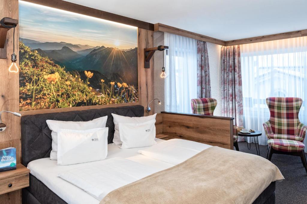 a bedroom with a bed with a mountain view at Hotel Tyrol in Oberstaufen