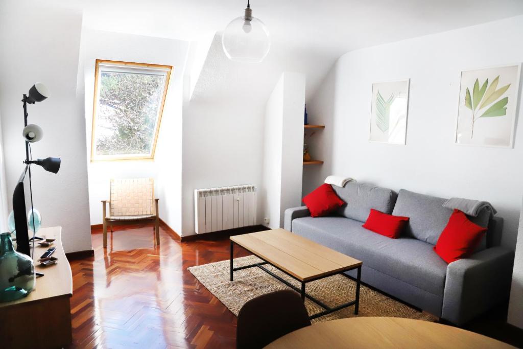 a living room with a gray couch and red pillows at Apartamento La Campa in Canfranc-Estación