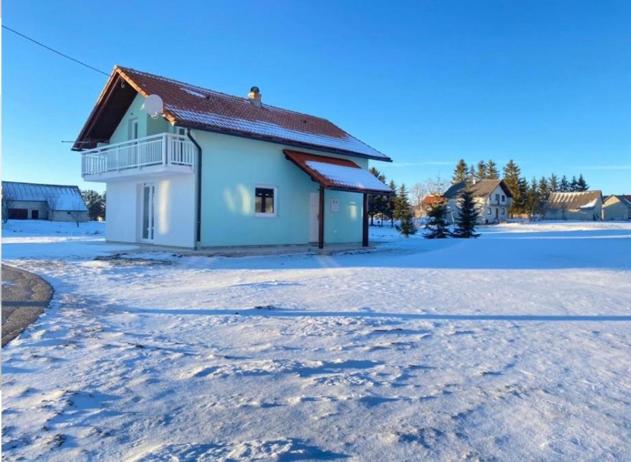 a house with snow on the ground in front of it at Vikend kuća Oskar in Kupres