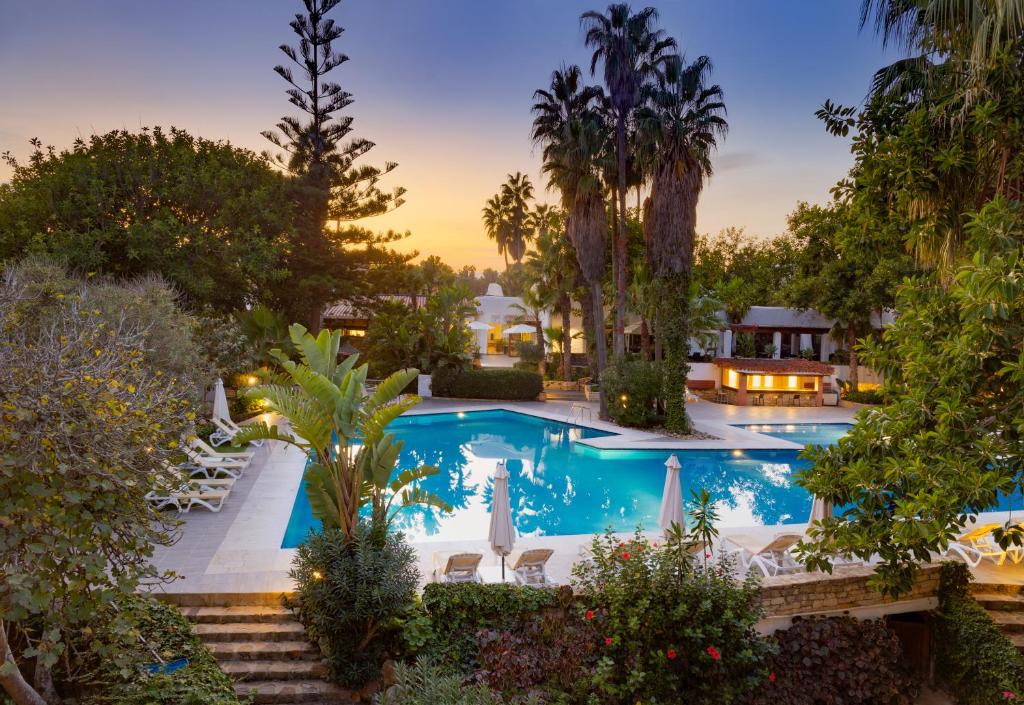 an image of a swimming pool with palm trees at Hotel Kabila in M'diq