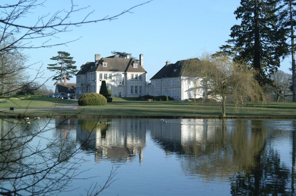 a large white house with a pond in front of it at Brockencote Hall in Kidderminster