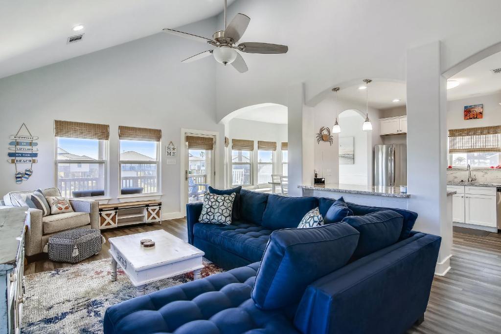 een woonkamer met blauwe banken en een plafondventilator bij Seaward Breeze in Galveston