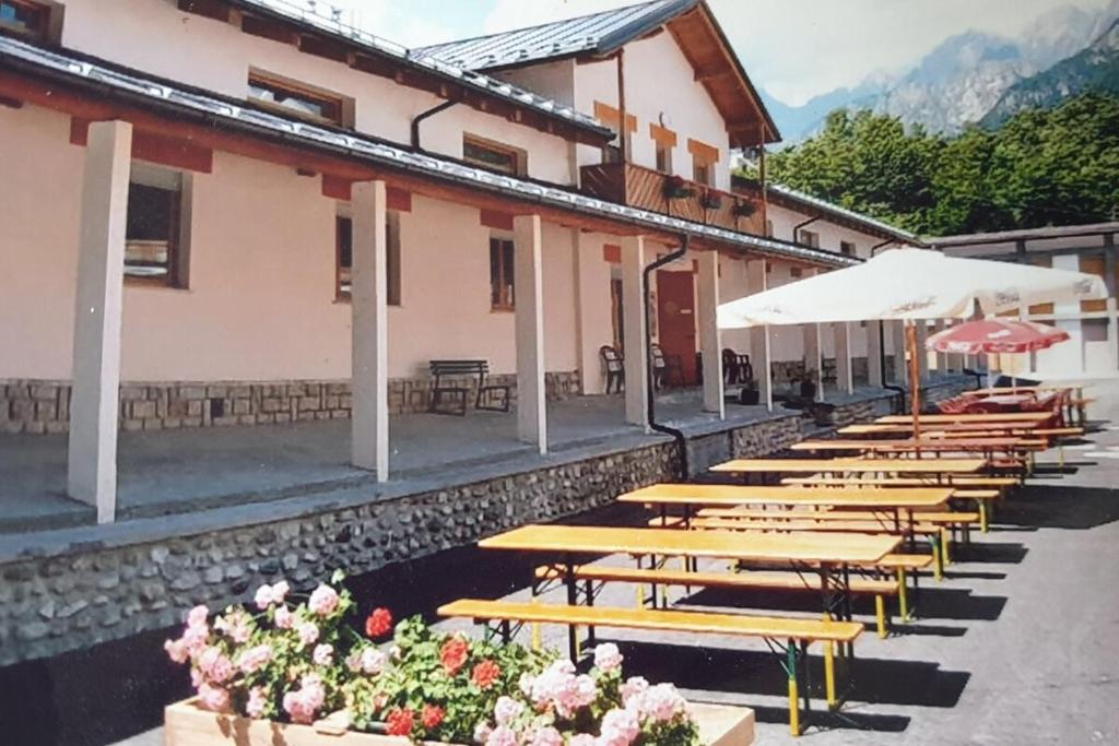 una fila di tavoli e ombrelloni in legno su un edificio di Lunga Via Delle Dolomiti a Calalzo