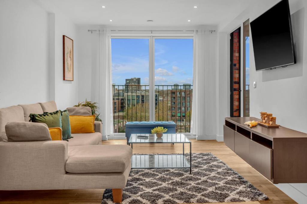 ein Wohnzimmer mit einem Sofa und einem TV in der Unterkunft Queen Elizabeth Olympic Park Apartment in London