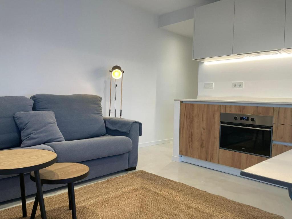 a living room with a blue couch and a kitchen at WASELA 114 in Palamós