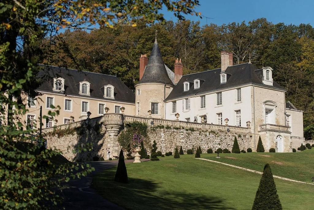 un castillo grande con una pared de piedra y árboles en Château De Beauvois - La Maison Younan en Saint-Étienne-de-Chigny