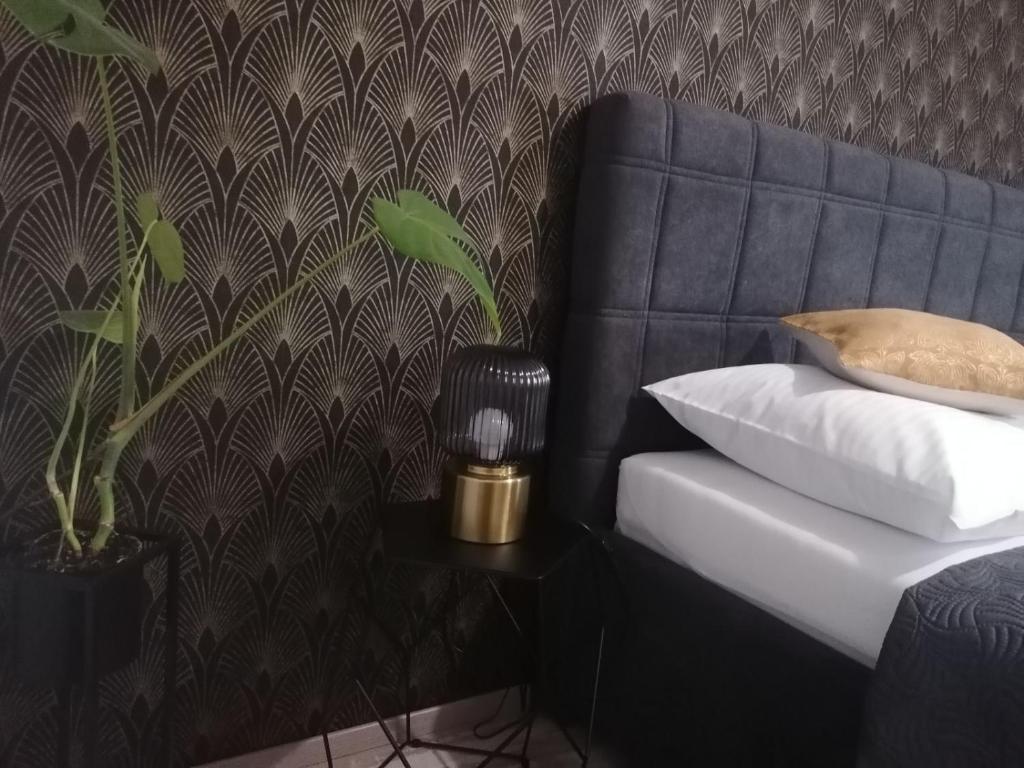 1 cama con almohada y una planta junto a la pared en Apartman Lipa, en Slavonski Brod