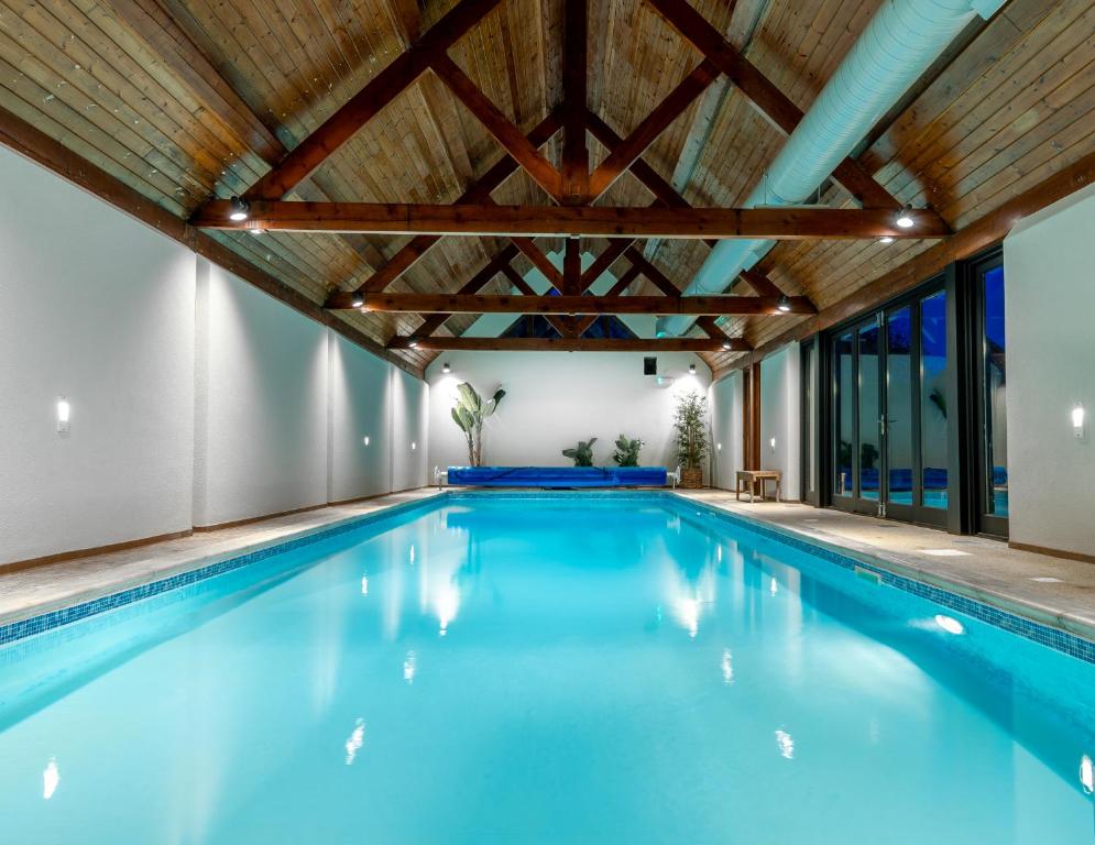 an indoor swimming pool with a wooden ceiling and blue water at Available For Contractors 2 Double Beds and Sofa Bed Private Parking in Harlow