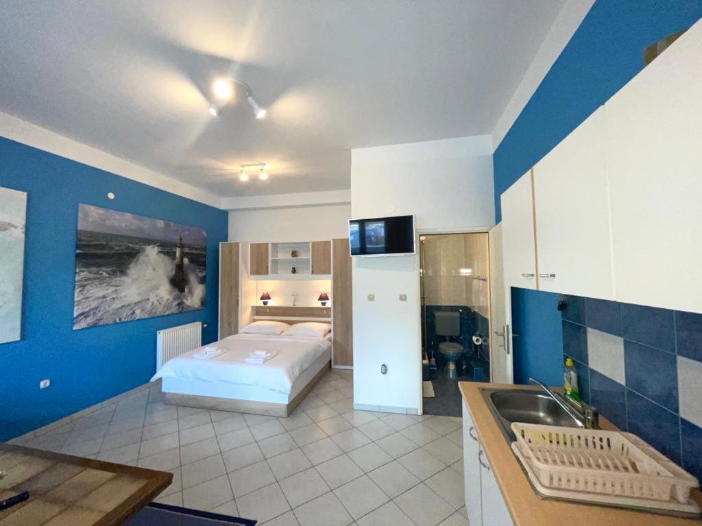 a bedroom with a bed and a kitchen with a sink at Apartmani Krajnović in Fažana