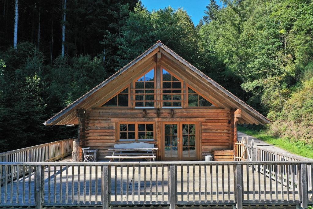 a log cabin with a large window on a porch at Schwarzwald Blockhaus - Sauna - Kamin - mit Bettwäsche und Handtücher in Schenkenzell