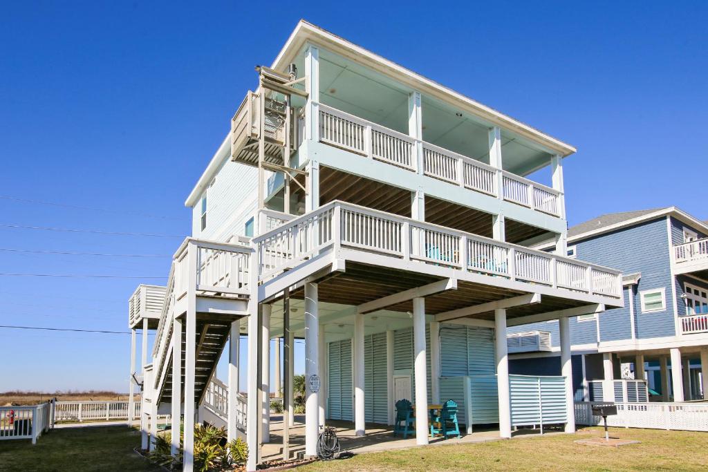 uma grande casa branca com escadas em Enchanted Beachfront by Ryson Vacation Rentals em Galveston