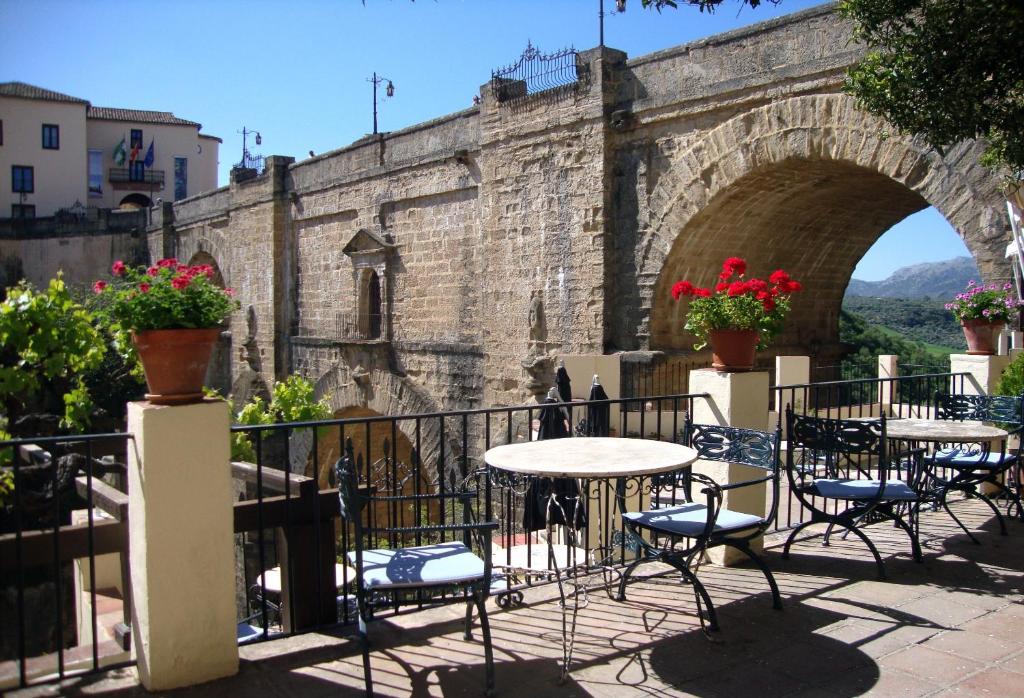 un patio avec des tables et des chaises en face d'un pont dans l'établissement Hotel Don Miguel, à Ronda