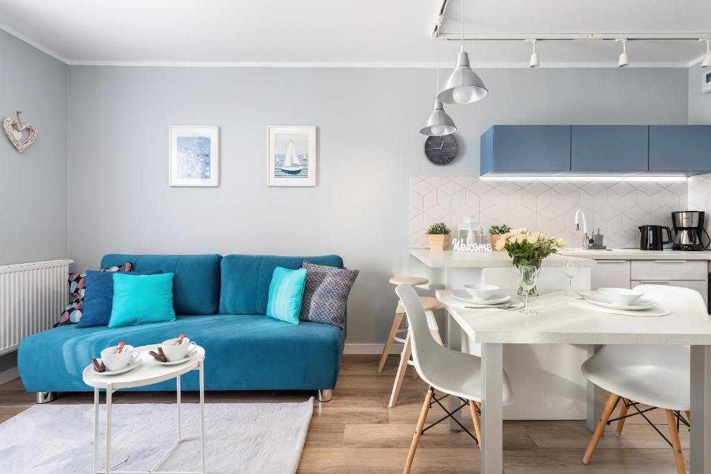 a living room with a blue couch and a table at Apartment Leśne Tarasy Dziwnówek by Renters in Dziwnówek