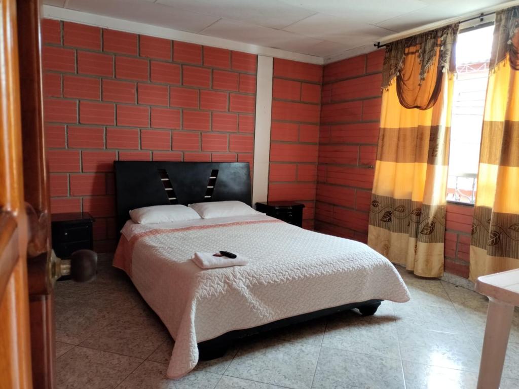 a bedroom with a bed and a red brick wall at Casa Hotel Los Faroles- Samaná/Caldas in Samaná