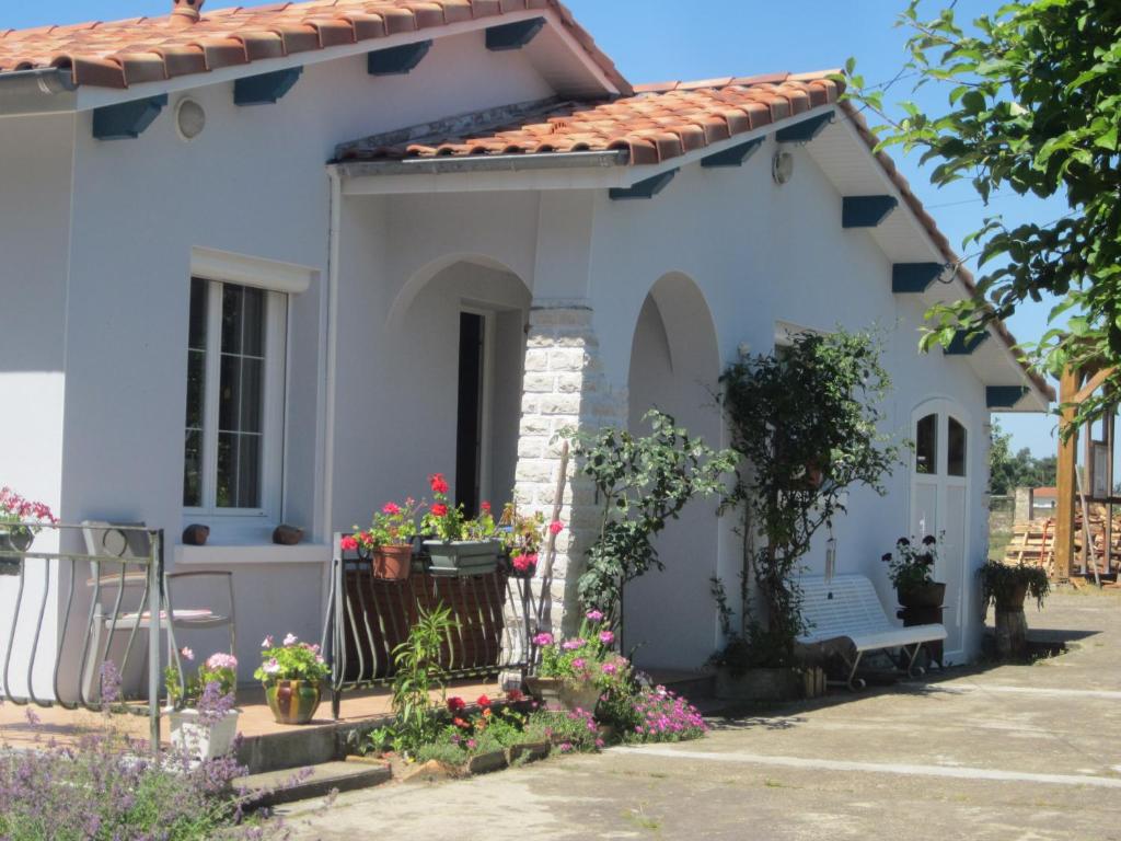 una casa blanca con flores delante en Chambre d'hôtes de la tuilerie, en Rion-des-Landes