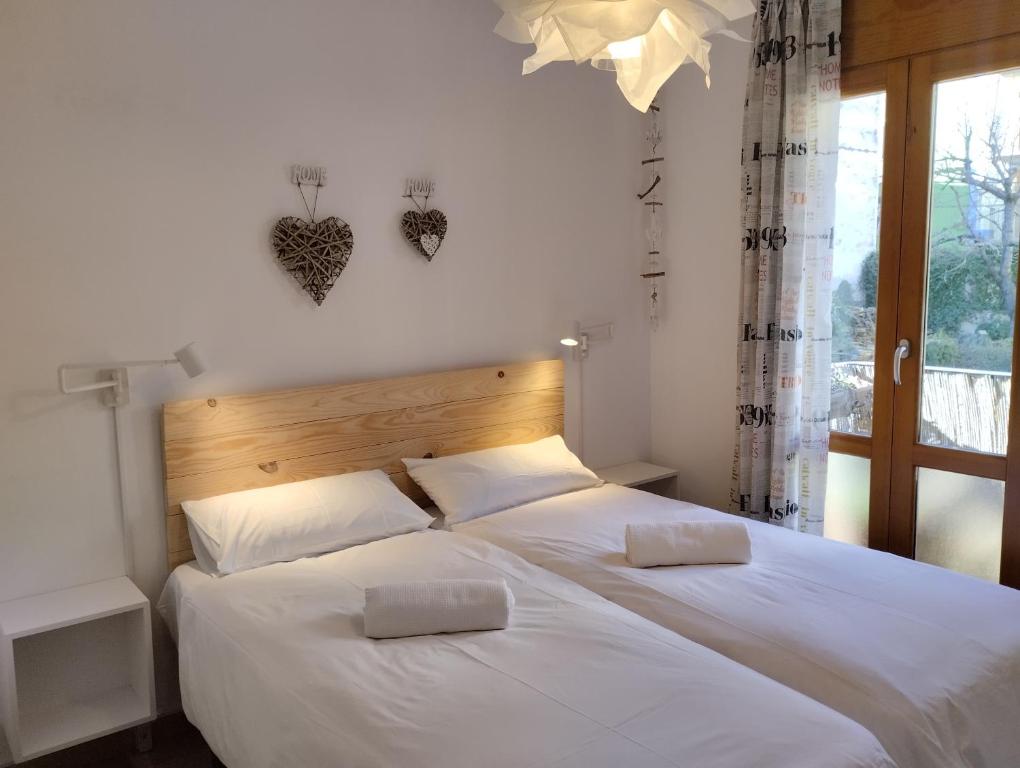 a bedroom with two beds with white sheets and a window at Casas Natura in Graus