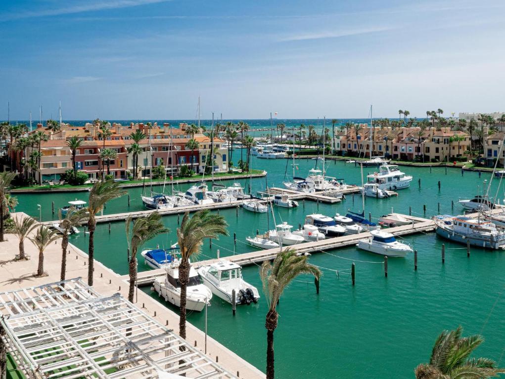 un puerto deportivo con barcos, palmeras y edificios en Ribera de Marlin 2357 Sotogrande, en San Roque