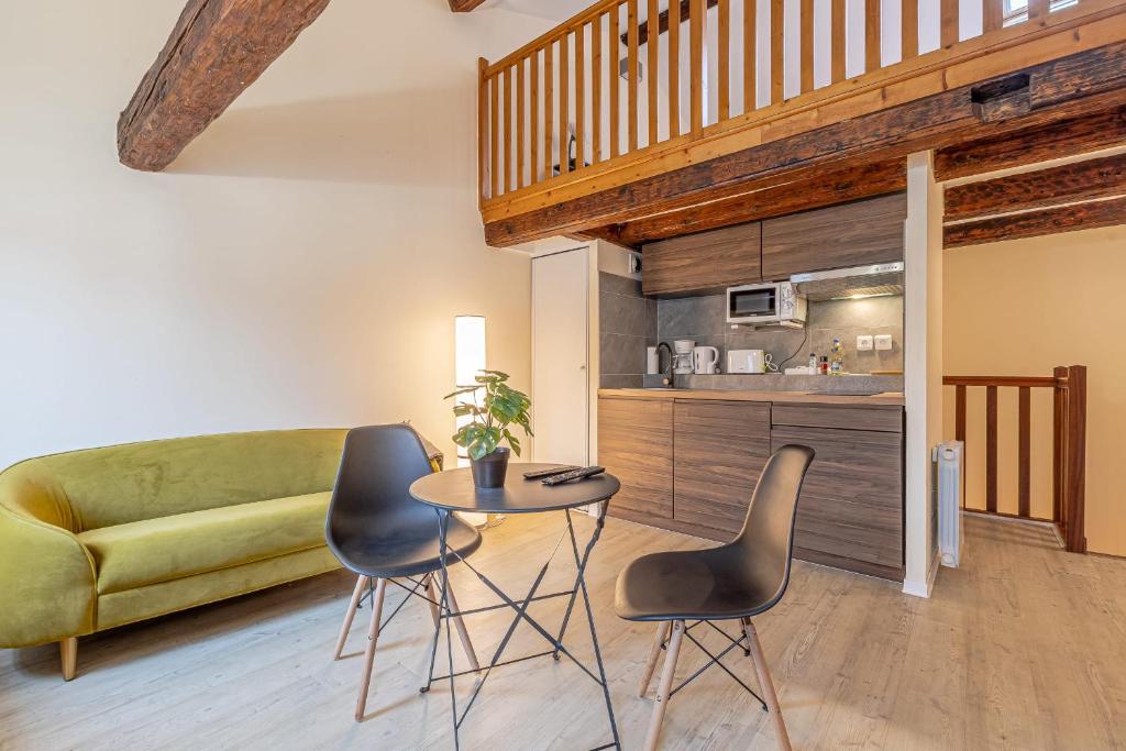 een woonkamer met een tafel en stoelen en een bank bij Sous les Toits de Stanislas in Nancy